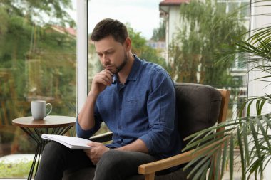 Evdeki koltukta sudoku çözen adam.