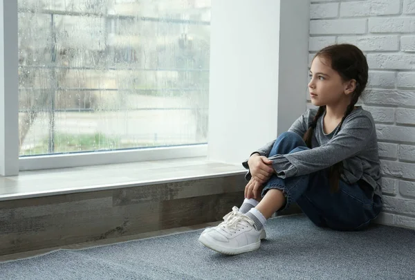 Trauriges Kleines Mädchen Sitzt Auf Dem Boden Neben Fenster Drinnen — Stockfoto