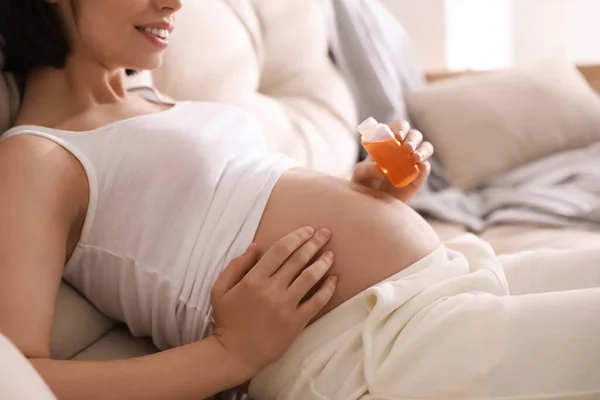 Jonge Zwangere Vrouw Met Cosmetische Product Bank Binnen Close — Stockfoto