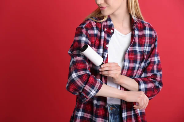 Jovem Mulher Limpando Roupas Com Rolo Fiapos Fundo Vermelho Close — Fotografia de Stock