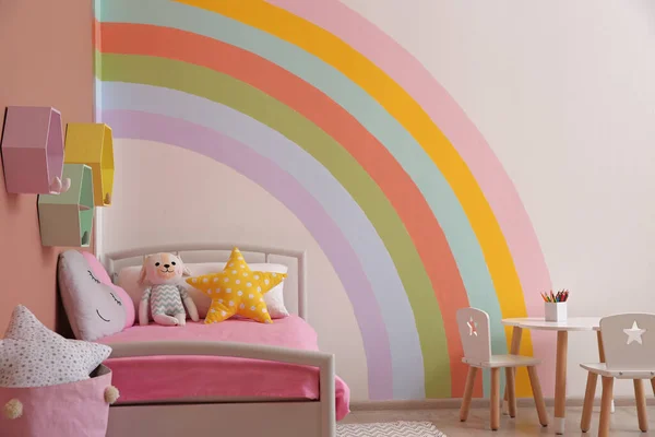 Cute child\'s room interior with beautiful rainbow painted on wall