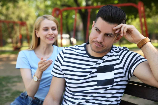 Displeased man ignoring overtalkative young woman during first date in park