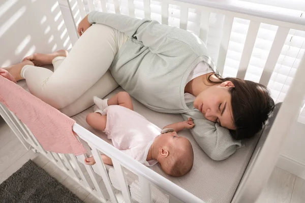 Tired Young Mother Sleeping Crib Her Baby Home View — Stock Photo, Image