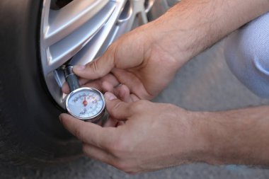 Dışarıdaki araba lastiklerindeki hava basıncını kontrol eden adam, yakın plan.