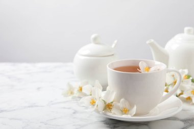 Aromatik yasemin çayı ve beyaz mermer masada taze çiçekler, metin için yer