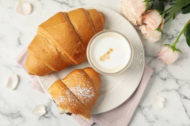 Lezzetli kruvasan, latte ve güllerle bembeyaz mermer masa üzerinde düz bir kompozisyon.