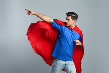 Gri arka planda süper kahraman pelerini giyen adam.