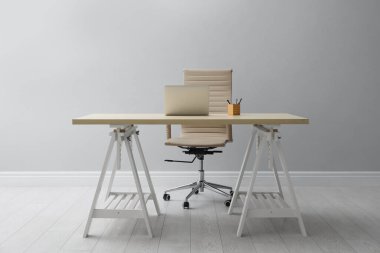 Dizüstü bilgisayarı olan şık bir iş yeri ve kapalı alandaki ışık duvarının yanında rahat bir koltuk. İç tasarım
