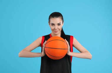 Açık mavi arka planda topu olan basketbolcu