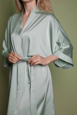 Zeytin zemininde açık yeşil ipek cüppeli güzel bir kadın, yakın plan.