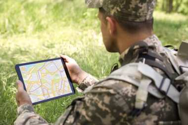 Ormanda tablet kullanan sırt çantalı asker