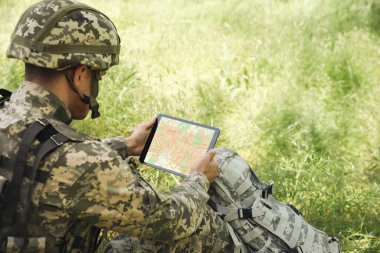 Ormanda tablet kullanan sırt çantalı asker