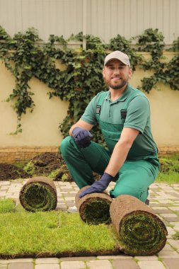 İşçi arka bahçedeki çimlerin üzerinde çimen açıyor.