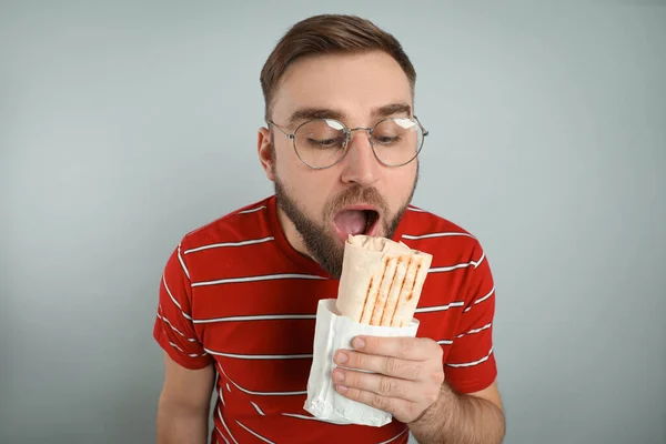 Young Man Eating Delicious Shawarma Grey Background — Stockfoto