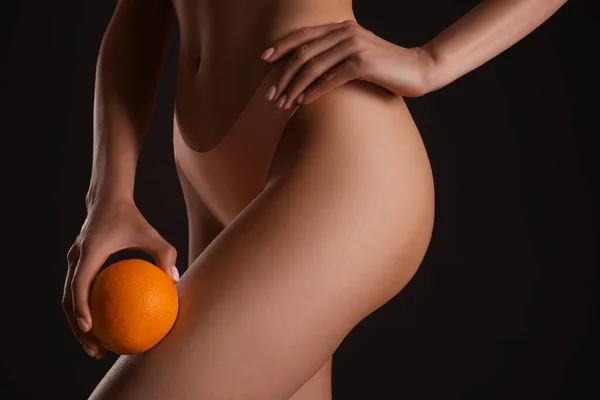 黒を背景にオレンジと下着でスリムな女性のクローズアップビュー セルライト問題の概念 — ストック写真
