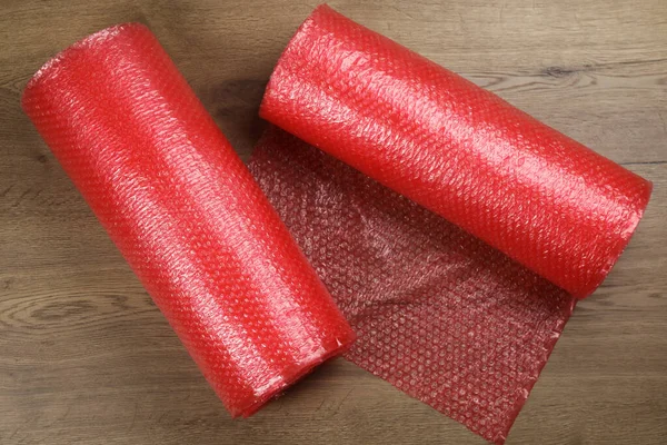 Bubble wrap rolls on wooden background, flat lay