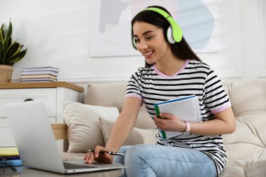 Evdeki kanepede oturup izleyen genç bir kadın.