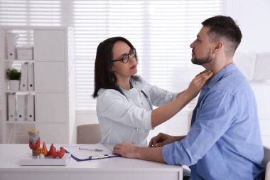 Hastanedeki hastanın tiroit bezini inceleyen doktor.