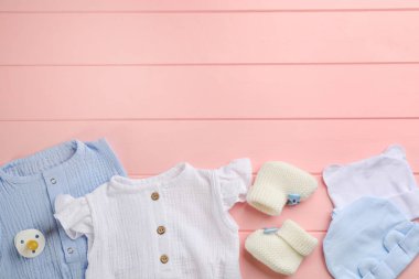 Bebek kıyafetleri ve aksesuarları pembe ahşap arka planda düz kompozisyon, metin için boşluk