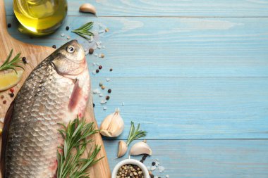 Taze çiğ sazan balığı ve açık mavi ahşap masa üzerindeki malzemeler, metin için yeri olan düz bir yer. Nehir balığı
