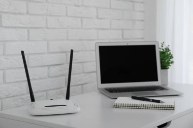 Yönlendirici, modern dizüstü bilgisayar ve beyaz masa içerisindeki defter