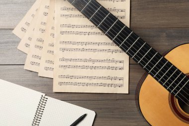 Tahta masa üzerinde gitar ve müzik notaları ile kompozisyon, düz yatıyordu