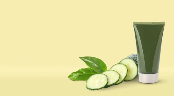Makeup remover, fresh cucumber and green leaves on yellow background. Space for text