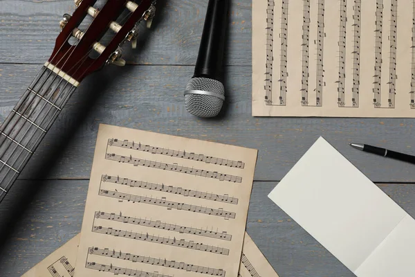 Composition with guitar and music notations on grey wooden table, flat lay