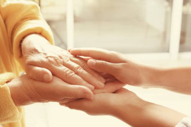 Bulanık arka planda ellere yardım etmek, yakın çekim. Yaşlılara bakım kavramı