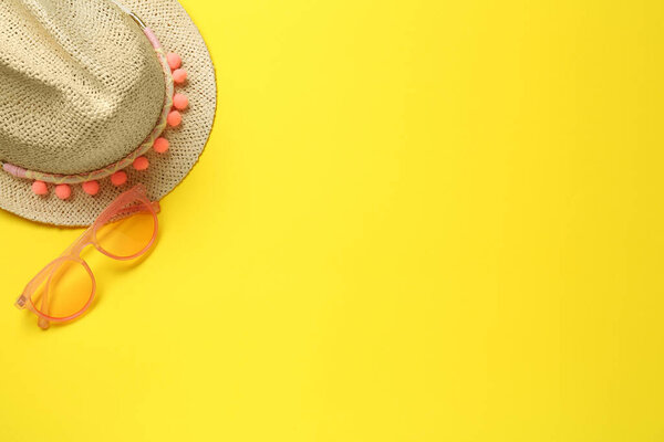 Hat and sunglasses on yellow background, flat lay with space for text. Sun protection accessories