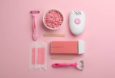 Pembe zemin üzerinde epilasyon araçları ve ürünleri, düz yatıyordu