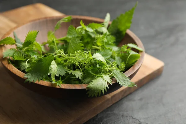 Färska Brännässlor Blad Trä Skål Svart Bord Närbild — Stockfoto