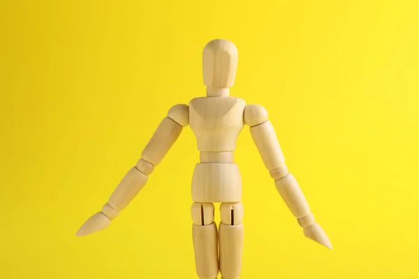 黄色の背景に木製の人間モデル ミニマネキン — ストック写真