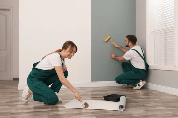 Mujer Aplicando Pegamento Sobre Papel Pared Mientras Hombre Colgando Hoja —  Fotos de Stock