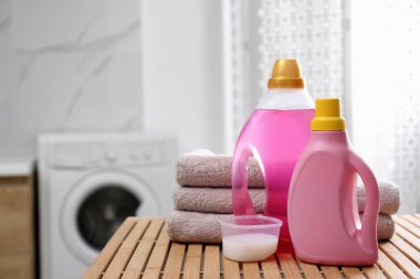 Katlanmış havlular ve deterjanlar banyodaki ahşap masanın üzerinde.