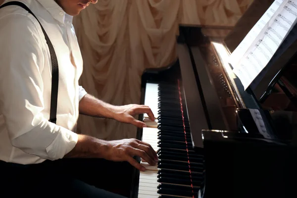 Man playing piano indoors, closeup. Talented musician