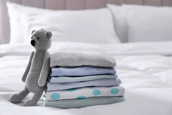 ベッドの上できれいな赤ちゃんの服やおもちゃのスタック — ストック写真