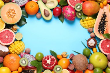 Açık mavi arka planda farklı egzotik meyvelerin çerçevesi düz. Metin için boşluk