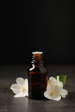 Temel yağ ve yasemin çiçekleri gri masada.