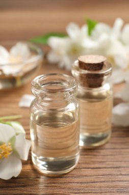 Yasemin yağı ve taze çiçekler ahşap masada.
