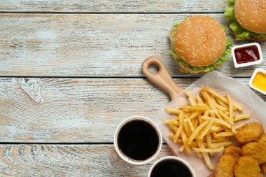 Düz kompozisyon ve beyaz ahşap masada lezzetli fast food menüsü. Metin için boşluk