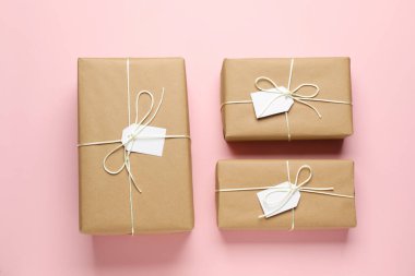 Pembe arka planda etiketleri olan ambalaj kağıtlarına sarılı paketler, düz konum