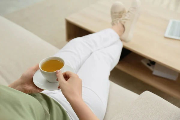 在家里沙发上喝杯热茶放松的年轻女人 — 图库照片