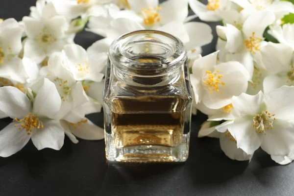 Ätherisches Jasminöl Und Frische Blumen Auf Dunkelgrauem Tisch — Stockfoto
