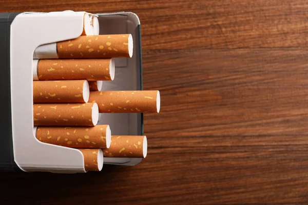 一袋香烟放在木制桌子上 可以看到上面 案文的篇幅 — 图库照片