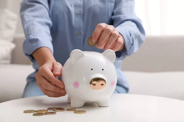 Woman Putting Coin Piggy Bank Table Indoors Closeup — Stock Photo, Image