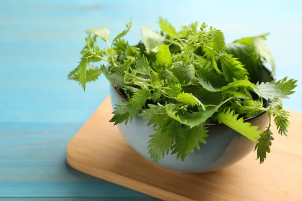 Färska Brännässlor Blad Skål Ljusblå Träbord Närbild — Stockfoto