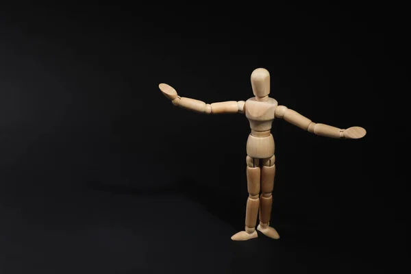 Wooden human model on black background, space for text. Mini mannequin