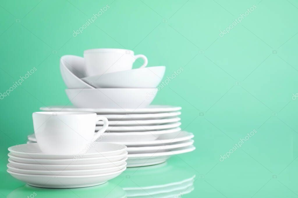 Set of clean tableware on light green background. Space for text