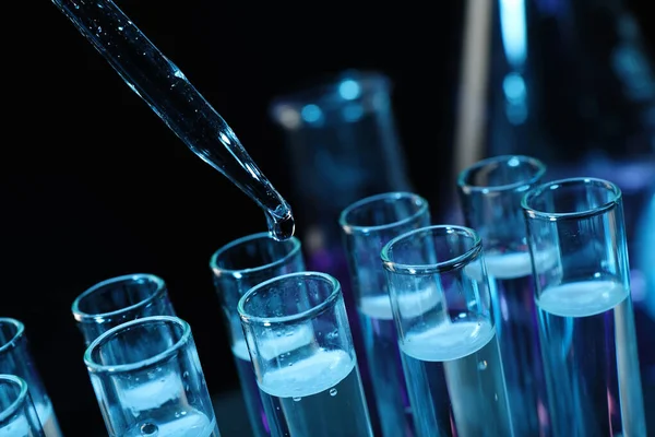 Siyah arkaplanda test tüpüne reaktör damlatılıyor, yakın plan. Laboratuvar analizi